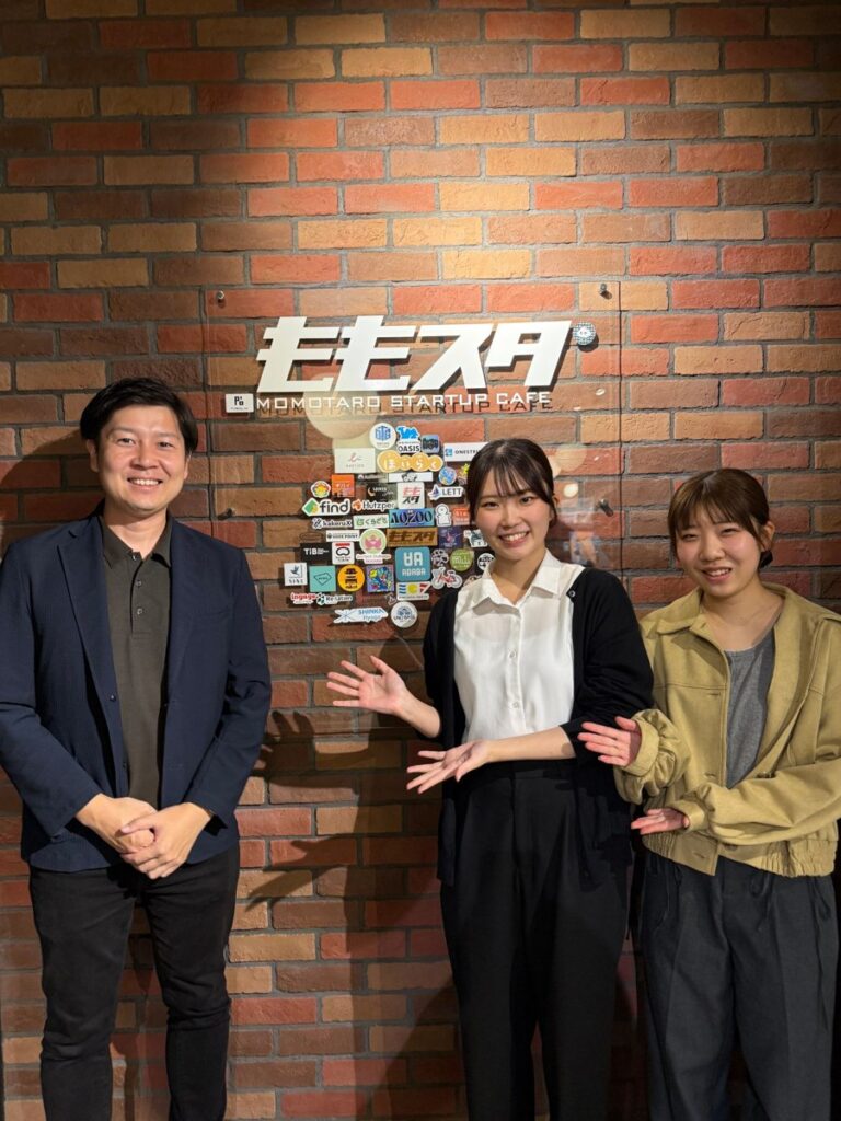 ももスタのロゴ前で、代表の平山とAegisの学生2名