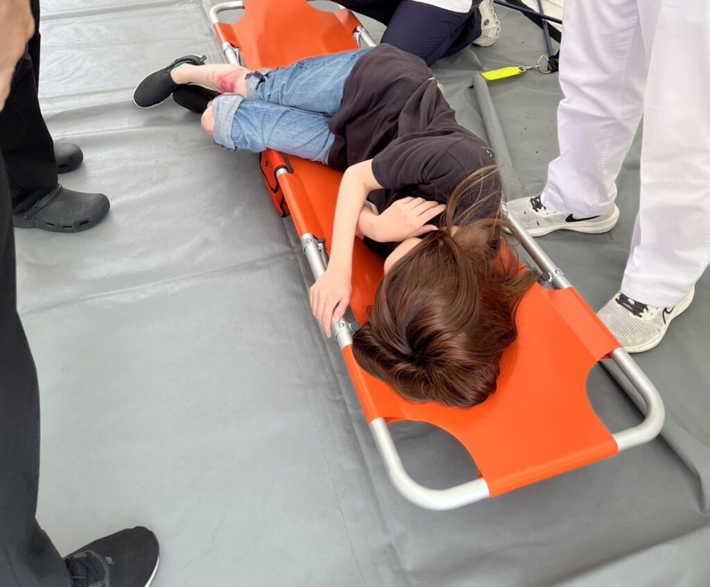 多数傷病者受け入れ訓練で、ストレッチャーに横たわる傷病者役の学生